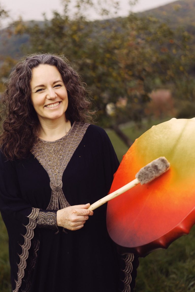 Mandy in schwarzem Kaftan mit rot-orange-gelber Schamanentrommel